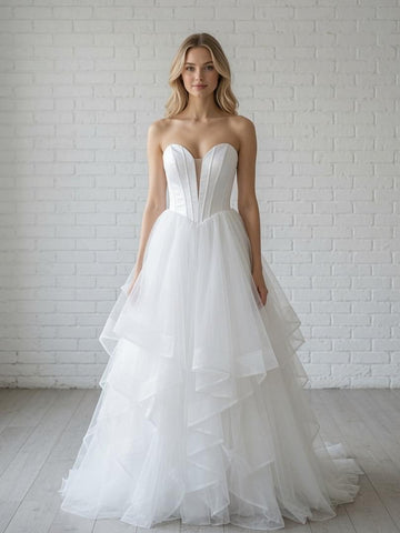 White debutante dress with a structured strapless corset bodice, plunging illusion sweetheart neckline, and a full layered tulle skirt with cascading ruffle details.