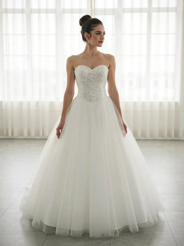 Woman wearing a strapless deb dress with beaded bodice in a bright room.