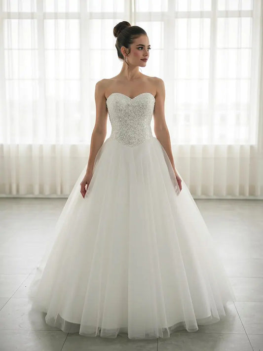 Woman wearing a strapless deb dress with beaded bodice in a bright room.