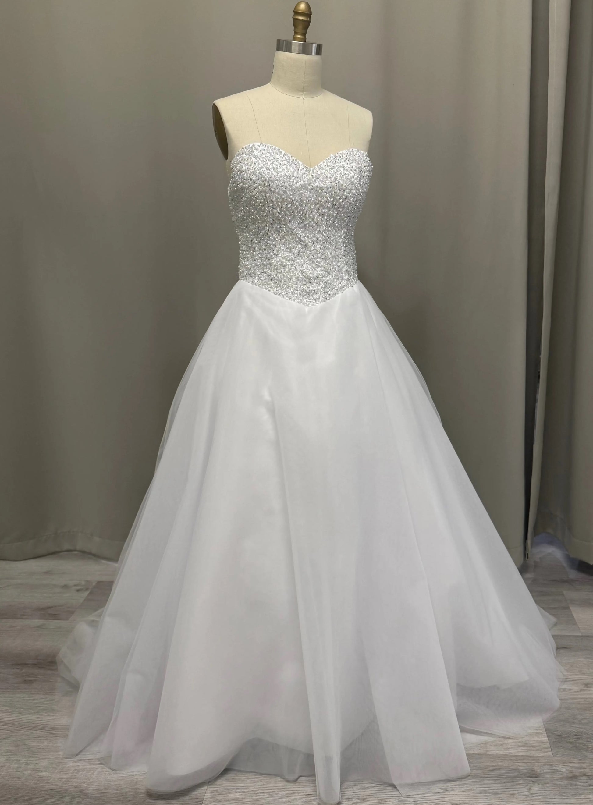 White deb dress with beaded top on a mannequin against a neutral background