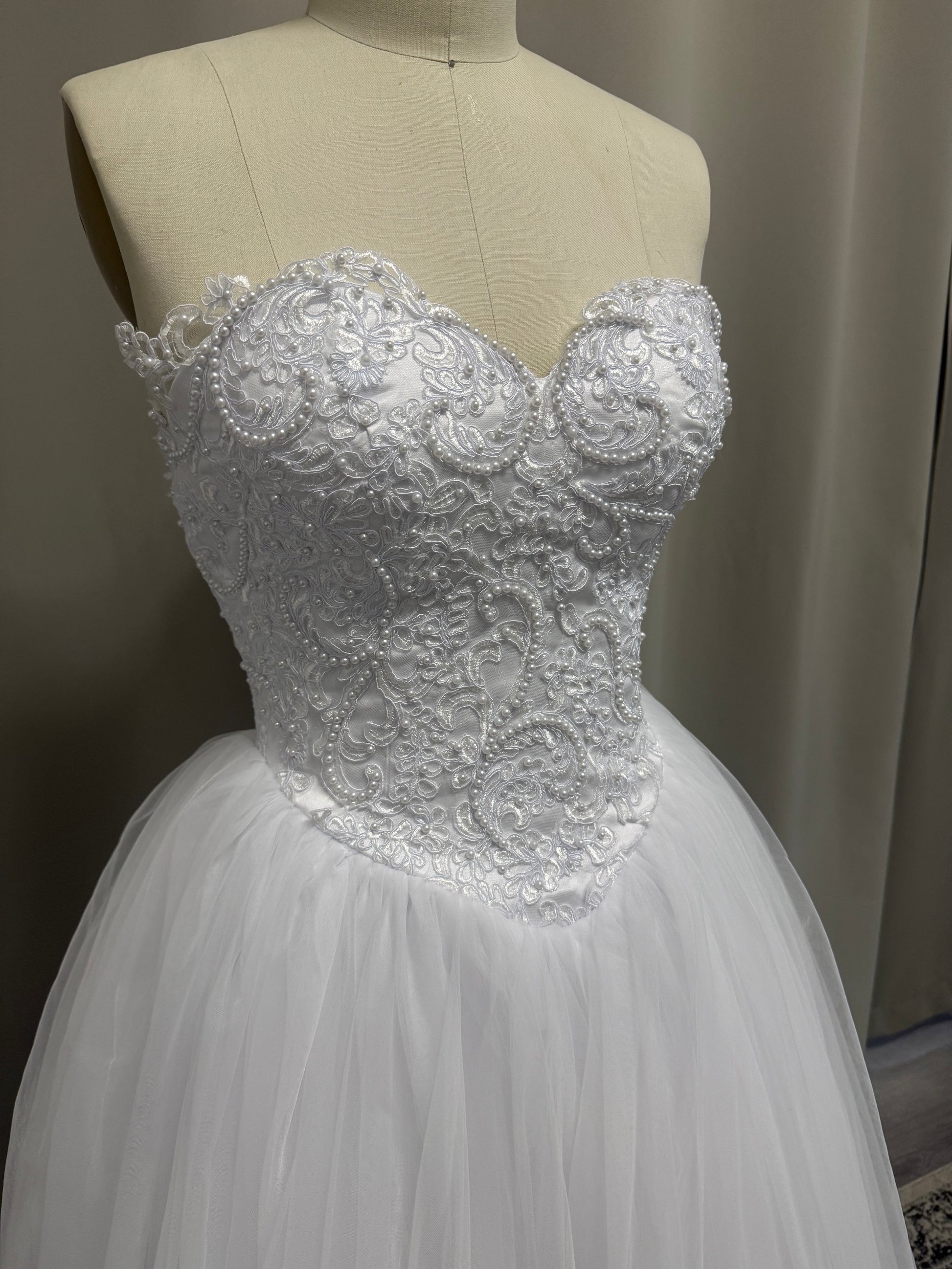 Close-up of Periana V1 formal debutante dress strapless sweetheart bodice with pearl and scroll lace appliqué
