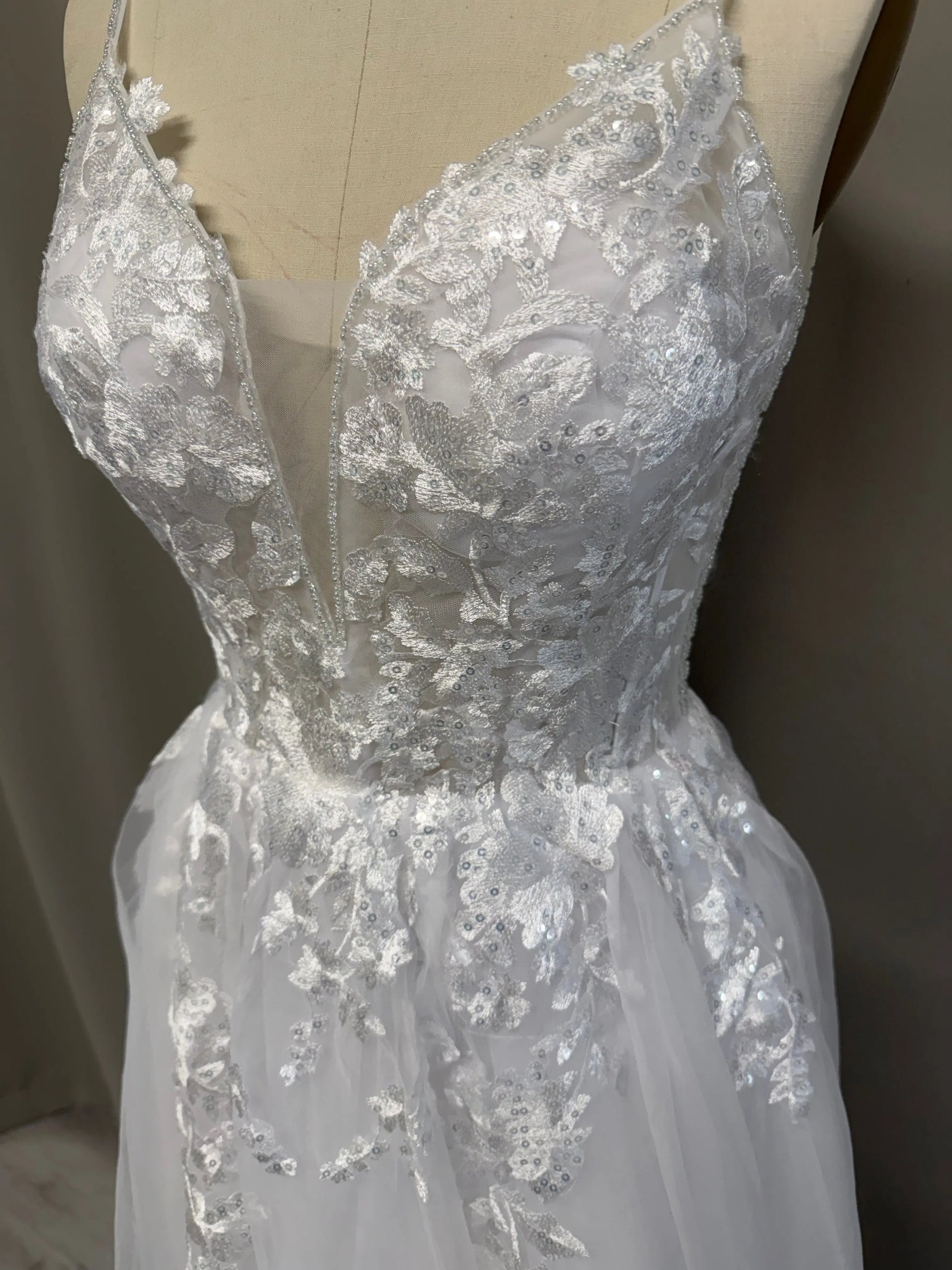 Close-up of the lace bodice featuring floral appliqués, sequins and an illusion plunge neckline.