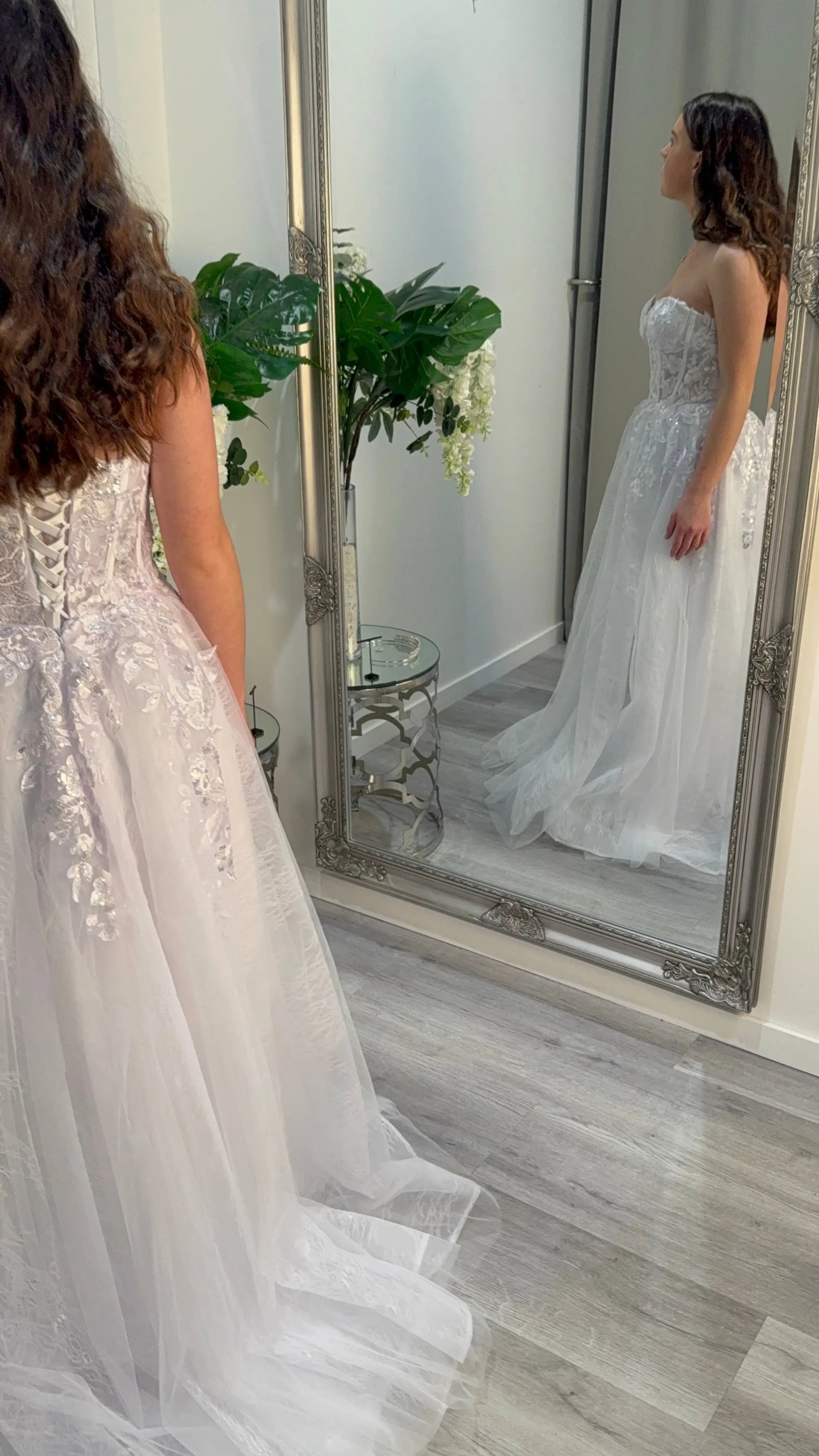 Woman in the Riley debutante dress standing side on in the mirror.