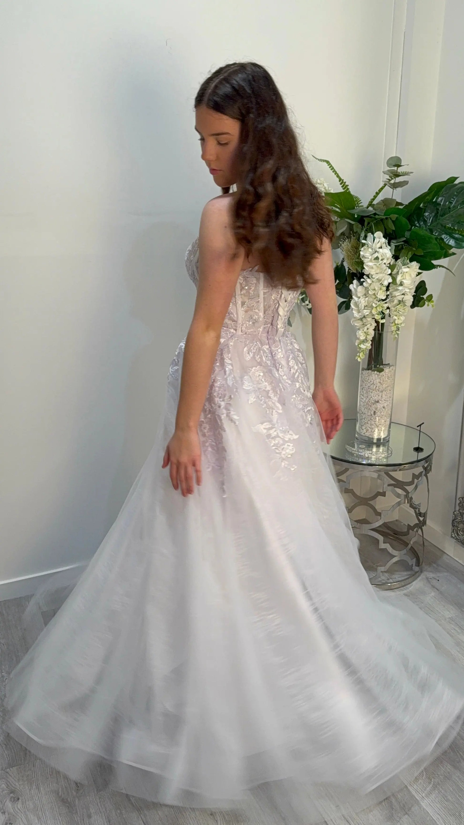 Woman in a white strapless gown spinning the dress