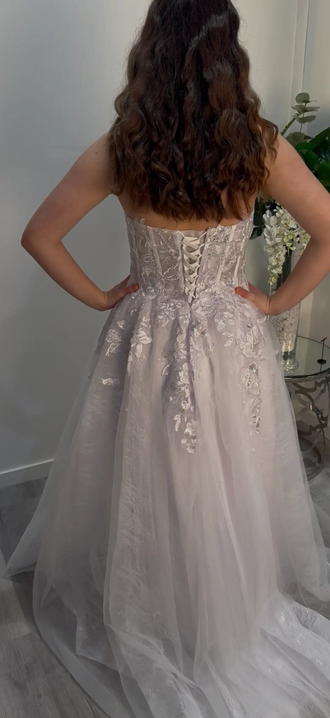 Woman wearing a sparkling silver gown showcasing the back