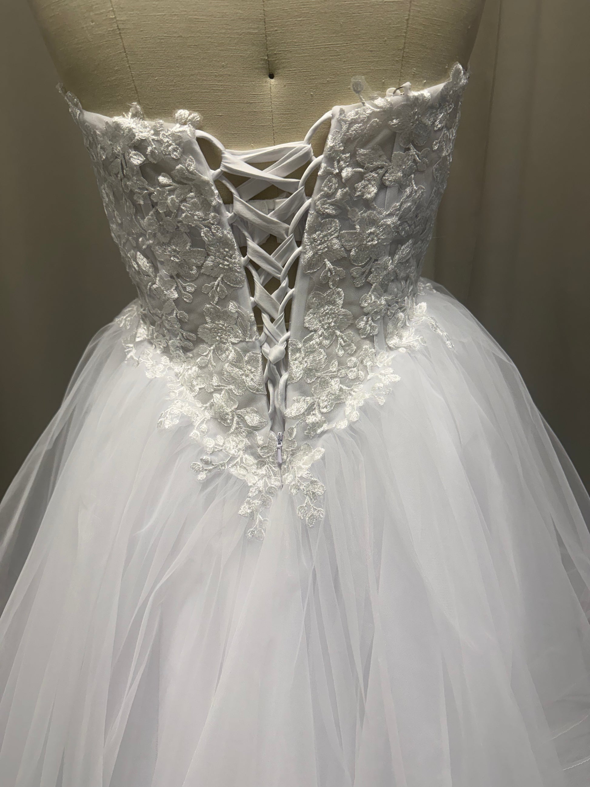 Riva debutante dress back view showing lace-up corset, floral lace appliqué and layered white tulle skirt