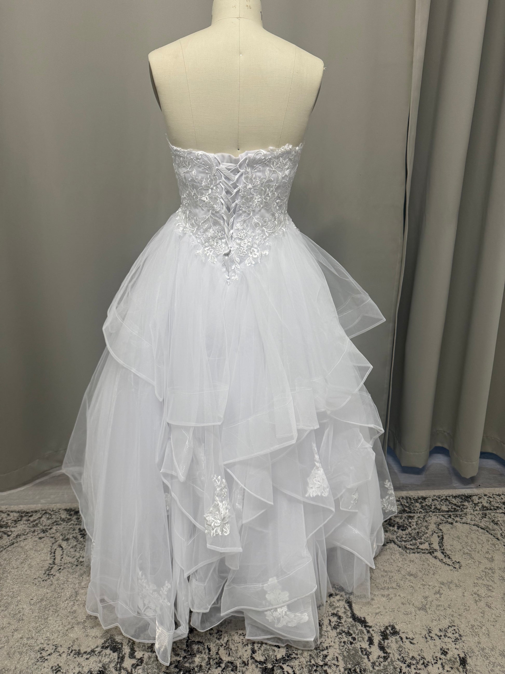 Willow V1 plunge neck debutante dress back view showing lace-up corset, floral lace and full white ruffle skirt