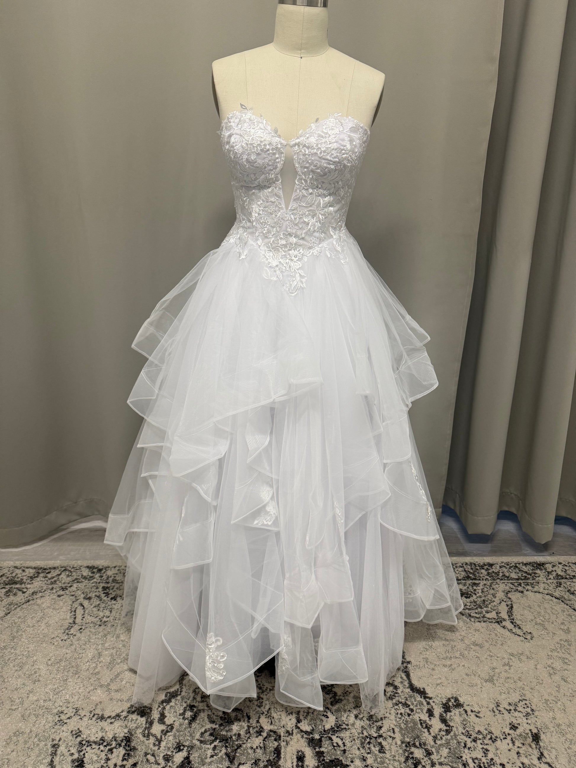 Willow V1 white plunge neck debutante dress, front view on mannequin with strapless lace corset and full ruffle skirt