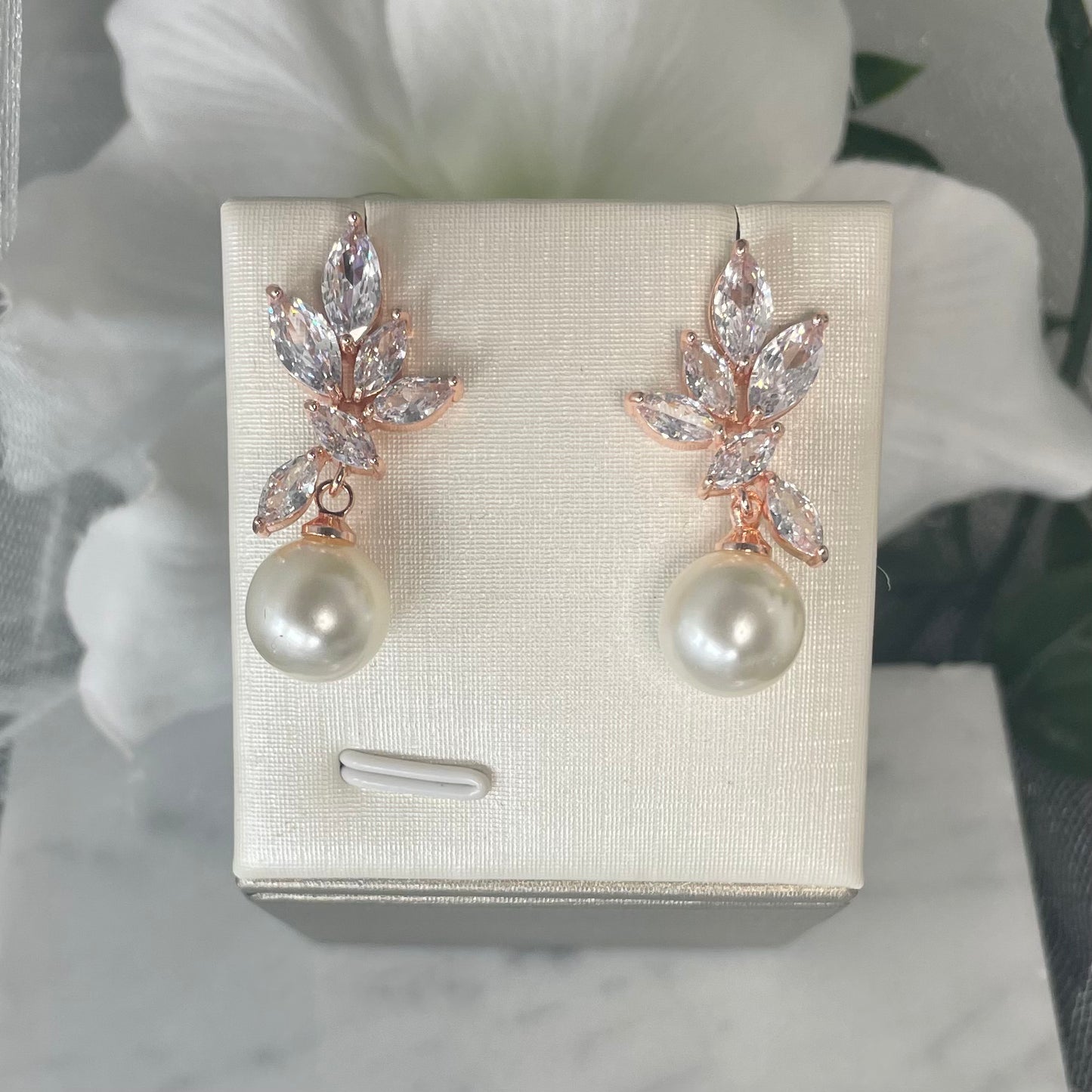 Celeste earrings with cascading leaf-like crystals and a central pearl in rose gold & silver.