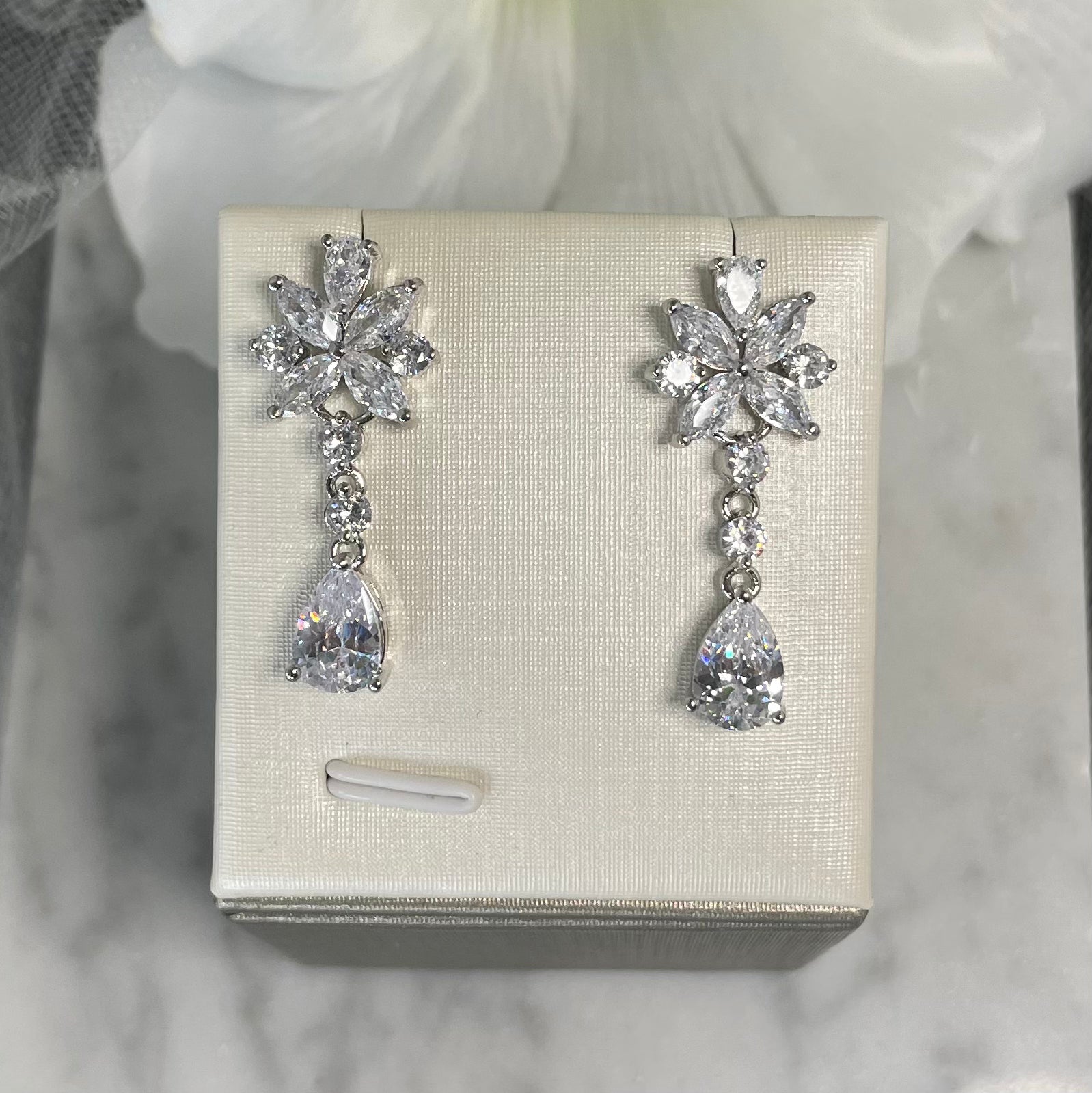 Christie cubic zirconia bridal earrings with a floral top, round crystals, and a teardrop finish, perfect for enhancing wedding day glamour.