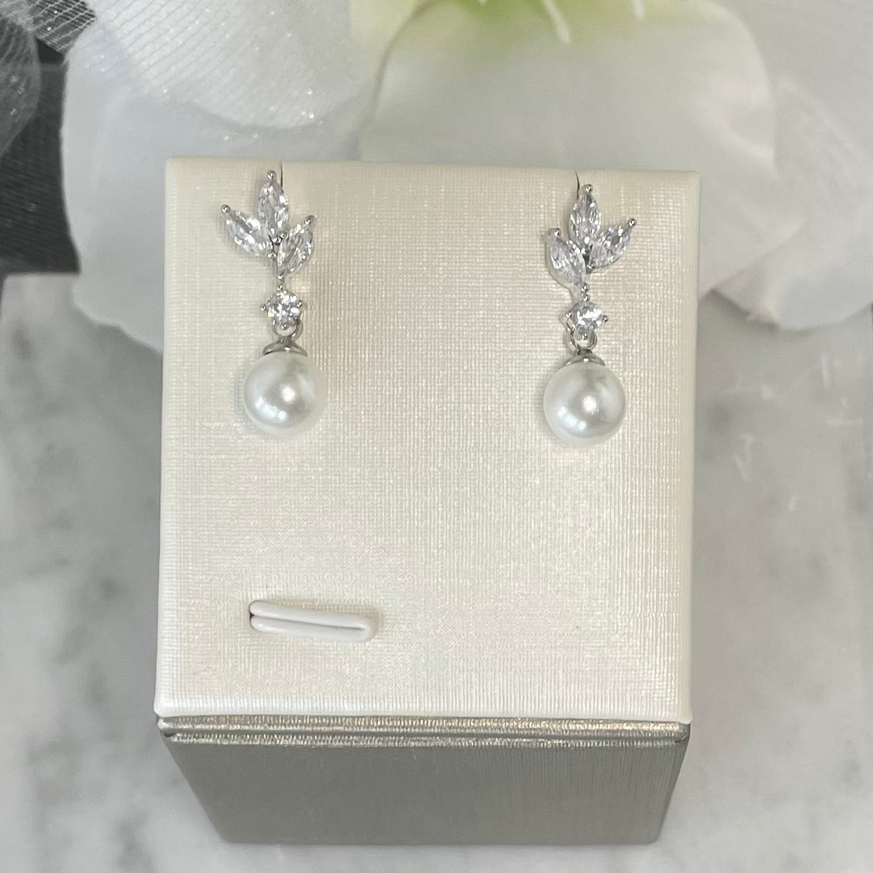 Selena leaf-design earrings with crystal embellishments and a dangling pearl accent.
