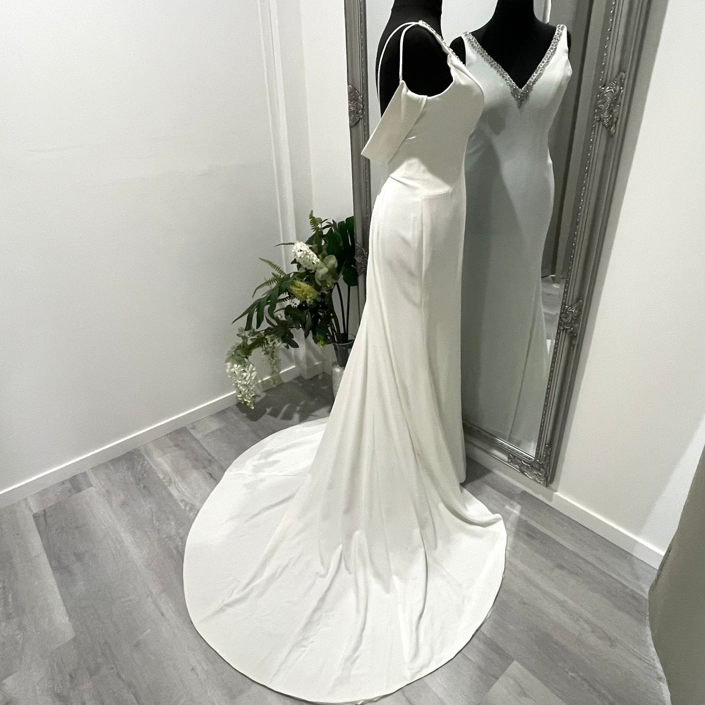 Bride in the Treasure wedding gown, highlighting the beaded V-neckline, draped cow back, and cascading chapel train.