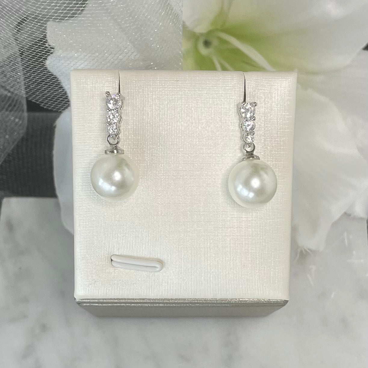 Close-up view of Everly Crystal Pearl Bridal Earrings featuring three varying-sized round crystals and a dangling pearl, perfect for elegant wedding day accessories.