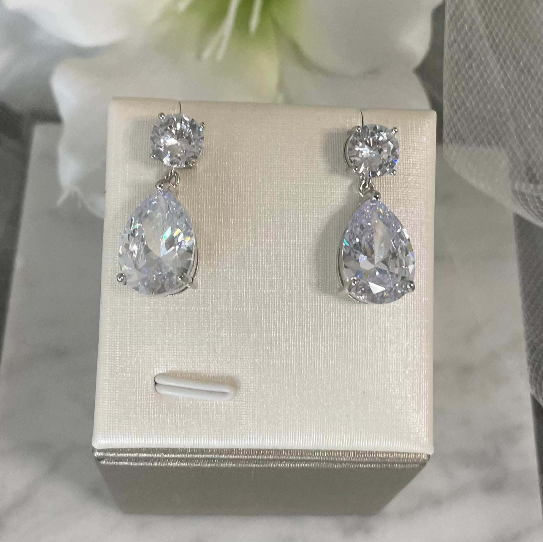 Sparkling Zoe Diamante Silver CZ Pear Shaped Drop Earrings featuring two distinct-sized cubic zirconia stones hanging from a small round CZ stone.