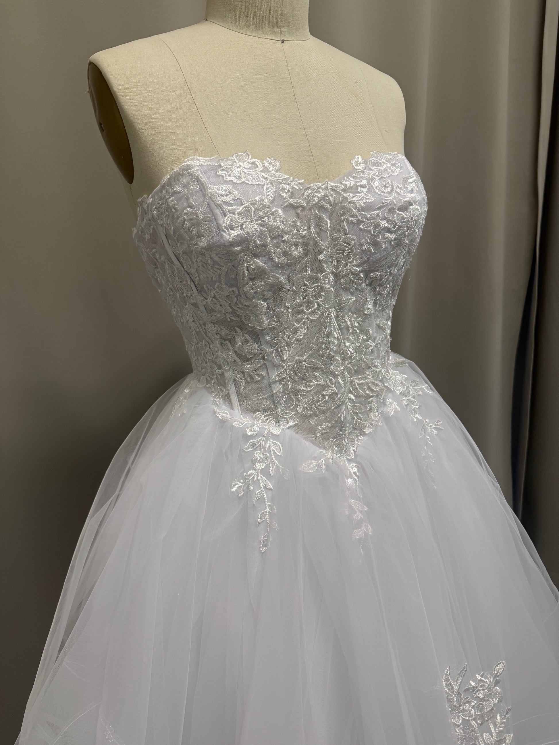 Close-up of Kasey V1 lace appliqué debutante dress strapless sweetheart bodice with floral lace and sheer panels