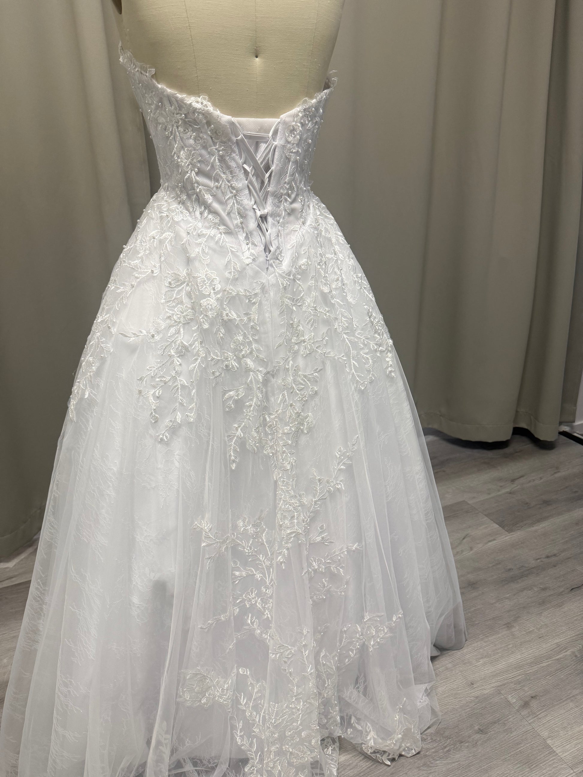 Lilly deb ball dress back view showing lace-up corset, floral lace appliqué and full white tulle skirt
