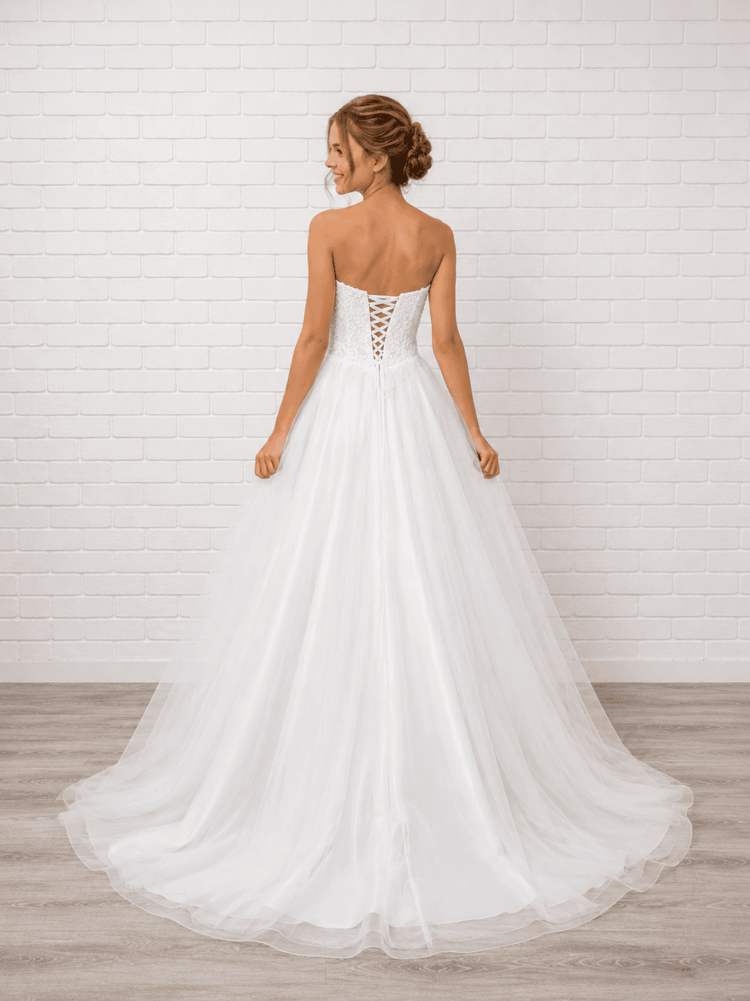 White debutante gown featuring a lace-up corset back, layered tulle skirt, and delicate lace appliqué detailing.