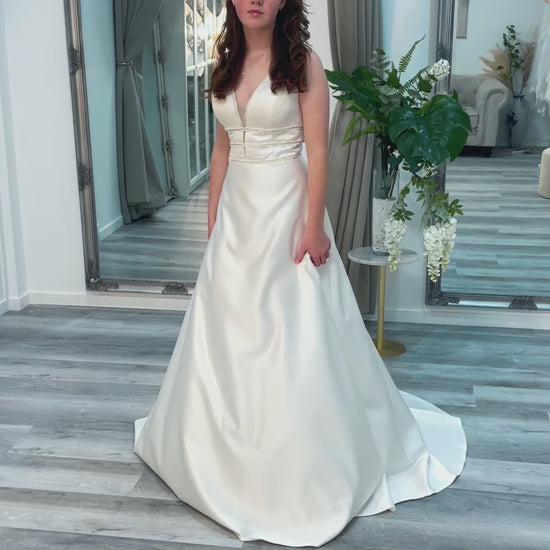 Bride in Chastity wedding gown, highlighting the V-neckline, beaded embellishments, and timeless A-line cut.